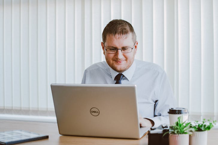 What is the difference between a job and a career - A man working using a laptop while smiling. 